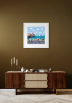 Framed artwork of a coastal scene with people on a brown wall above a wooden sideboard.